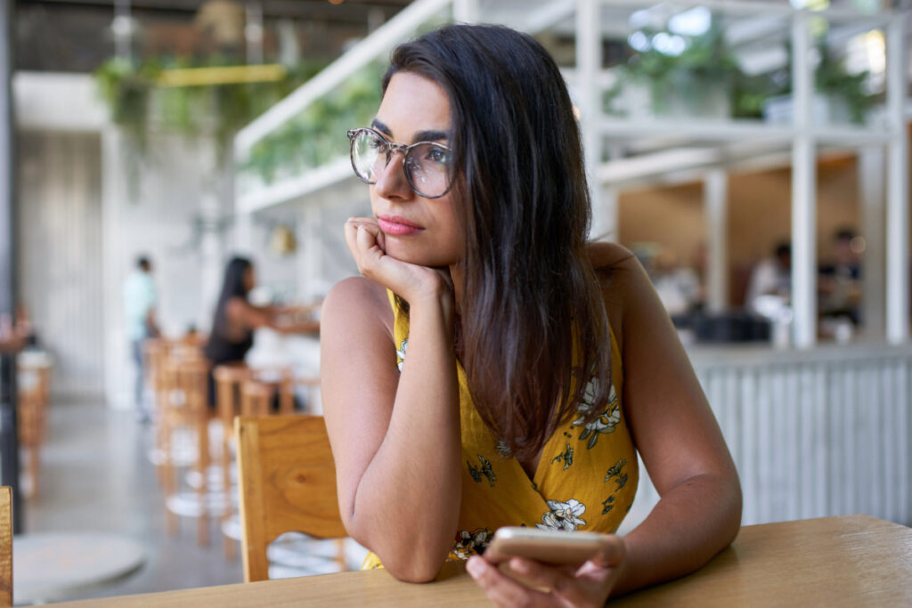 Frau sitzt nachdenklich im Café – Gedanken über Stress und Lebensbalance