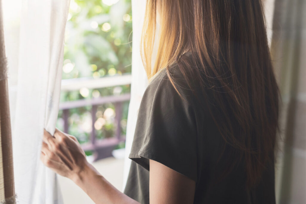 Frau blickt nach draußen und atmet ruhig – Embodiment und Achtsamkeit